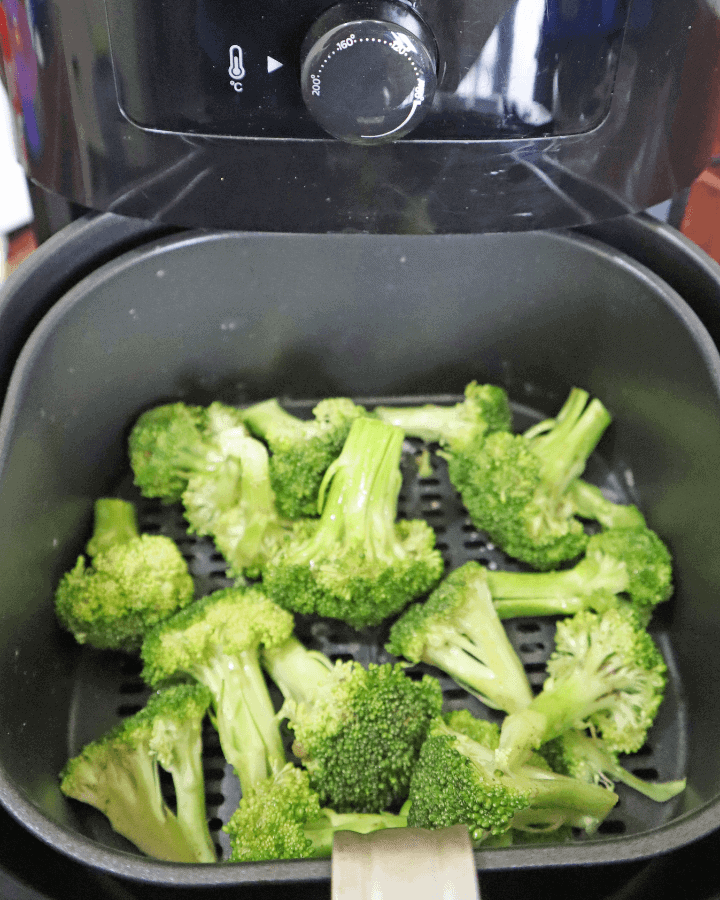 place seasoned broccoli in air fryer basket